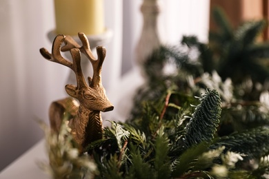Decorative reindeer figure near fir tree branches, closeup. Christmas decorations