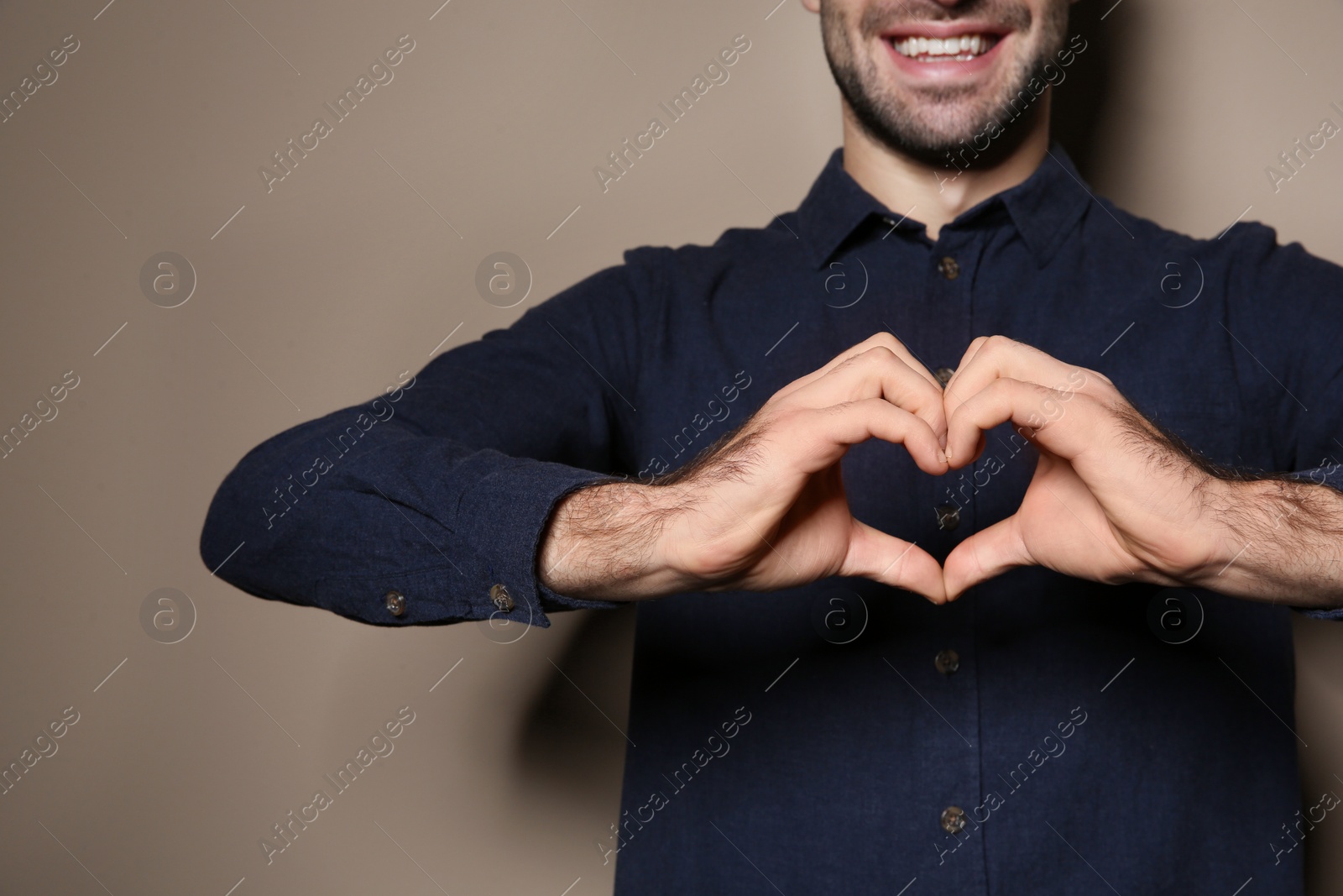 Photo of Man showing HEART gesture in sign language on color background, closeup