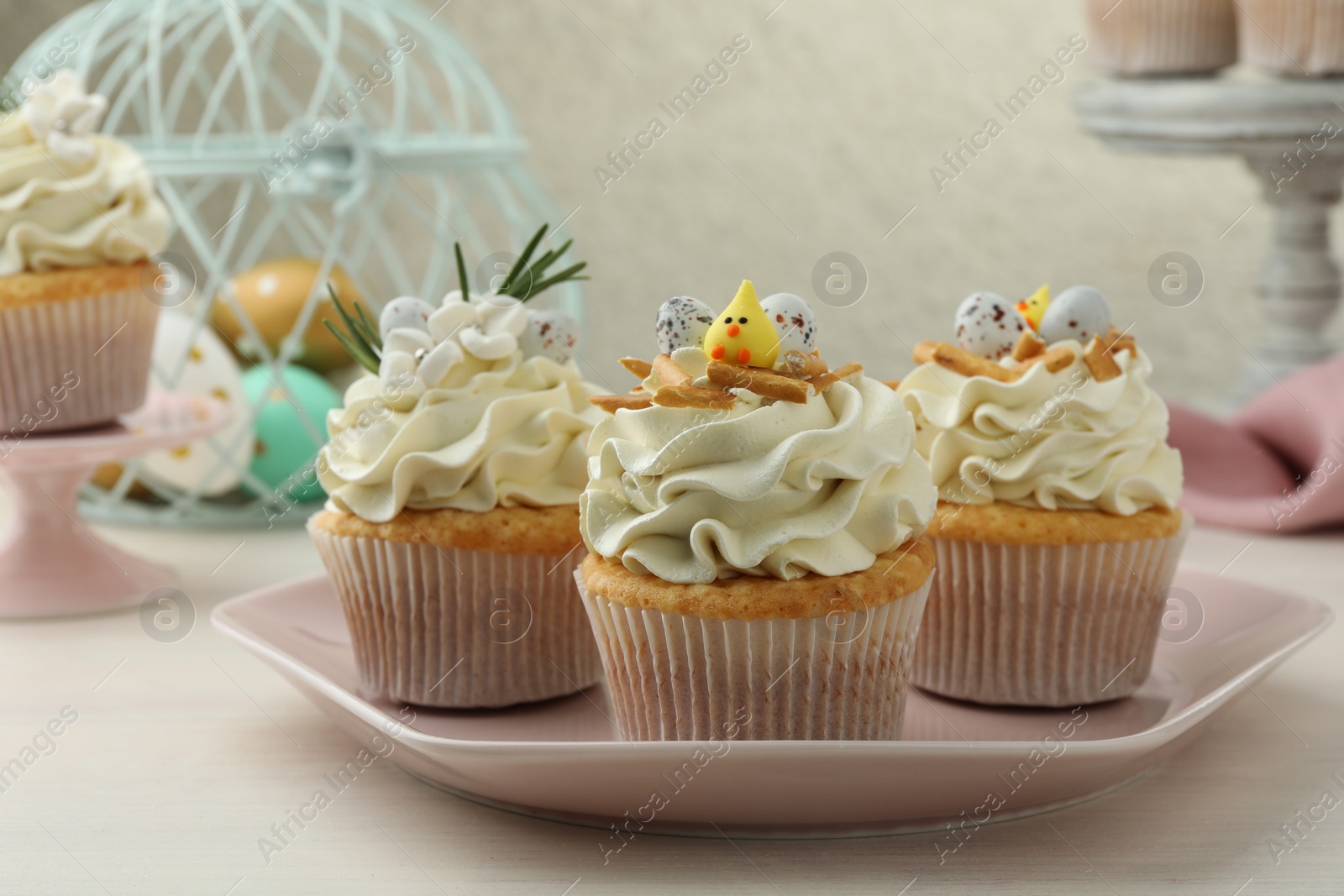 Photo of Tasty Easter cupcakes with vanilla cream on light wooden table