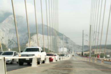 Photo of Blurred view of modern bridge and cars near mountain