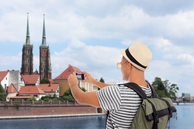 Traveler with backpack taking photo in foreign city during summer vacation