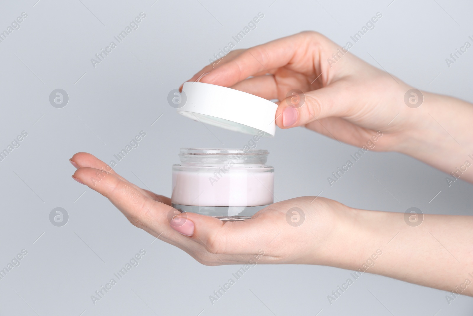 Photo of Woman with jar of cream on grey background, closeup