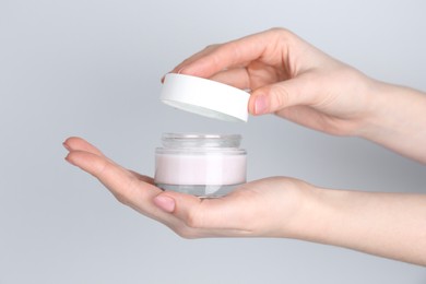 Woman with jar of cream on grey background, closeup