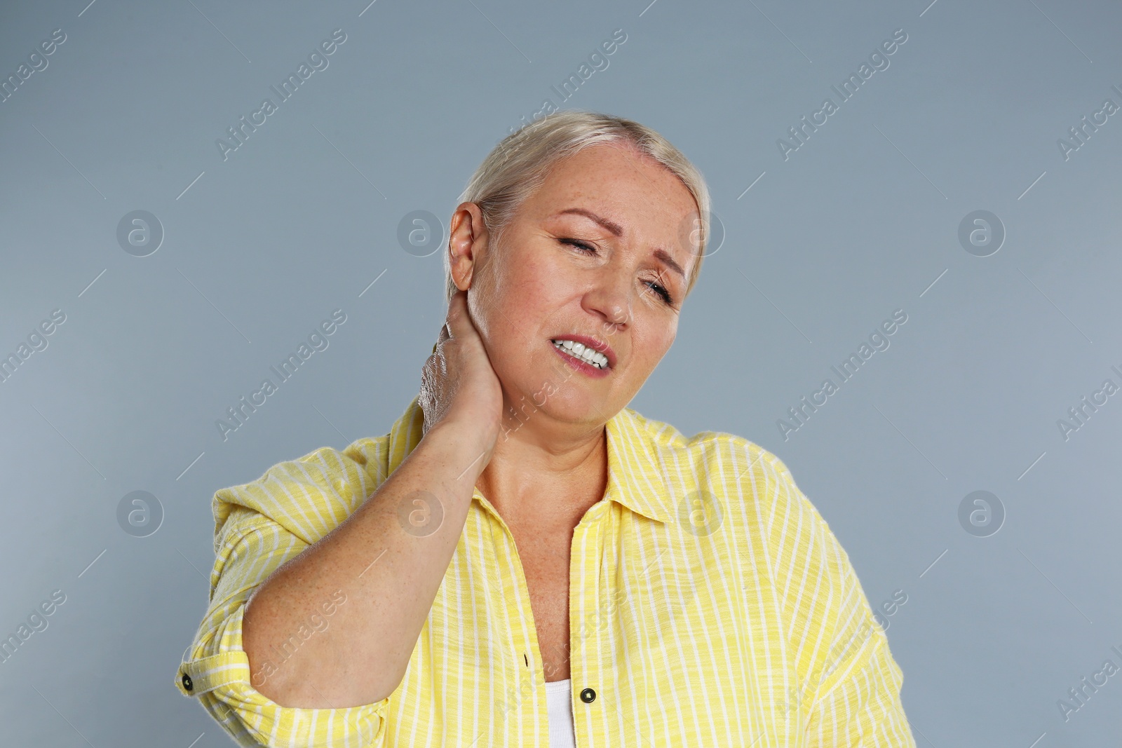 Image of Mature woman suffering from neck pain on grey background