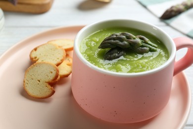 Photo of Delicious asparagus soup served on table, closeup
