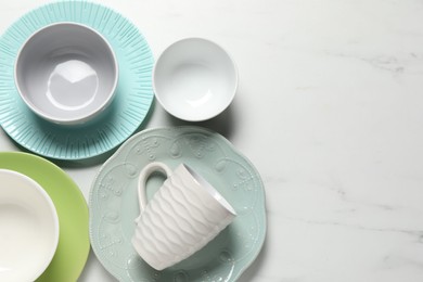 Photo of Beautiful ceramic dishware and cup on white marble table, flat lay. Space for text