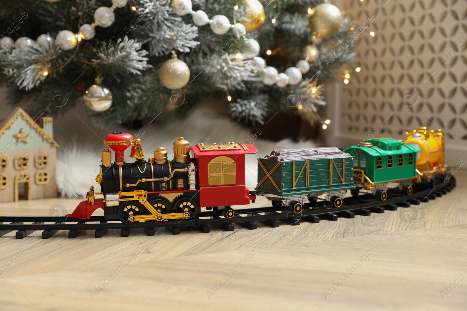 Photo of Toy train and railway near Christmas tree indoors