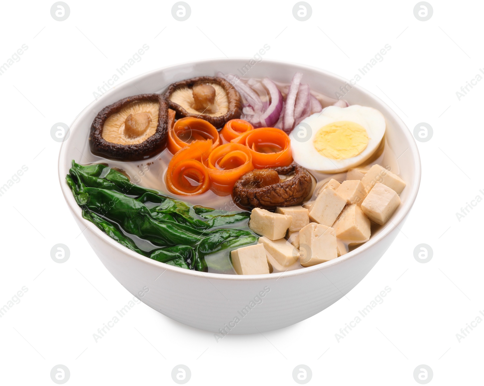 Photo of Delicious vegetarian ramen with egg, mushrooms, tofu and vegetables in bowl isolated on white. Noodle soup