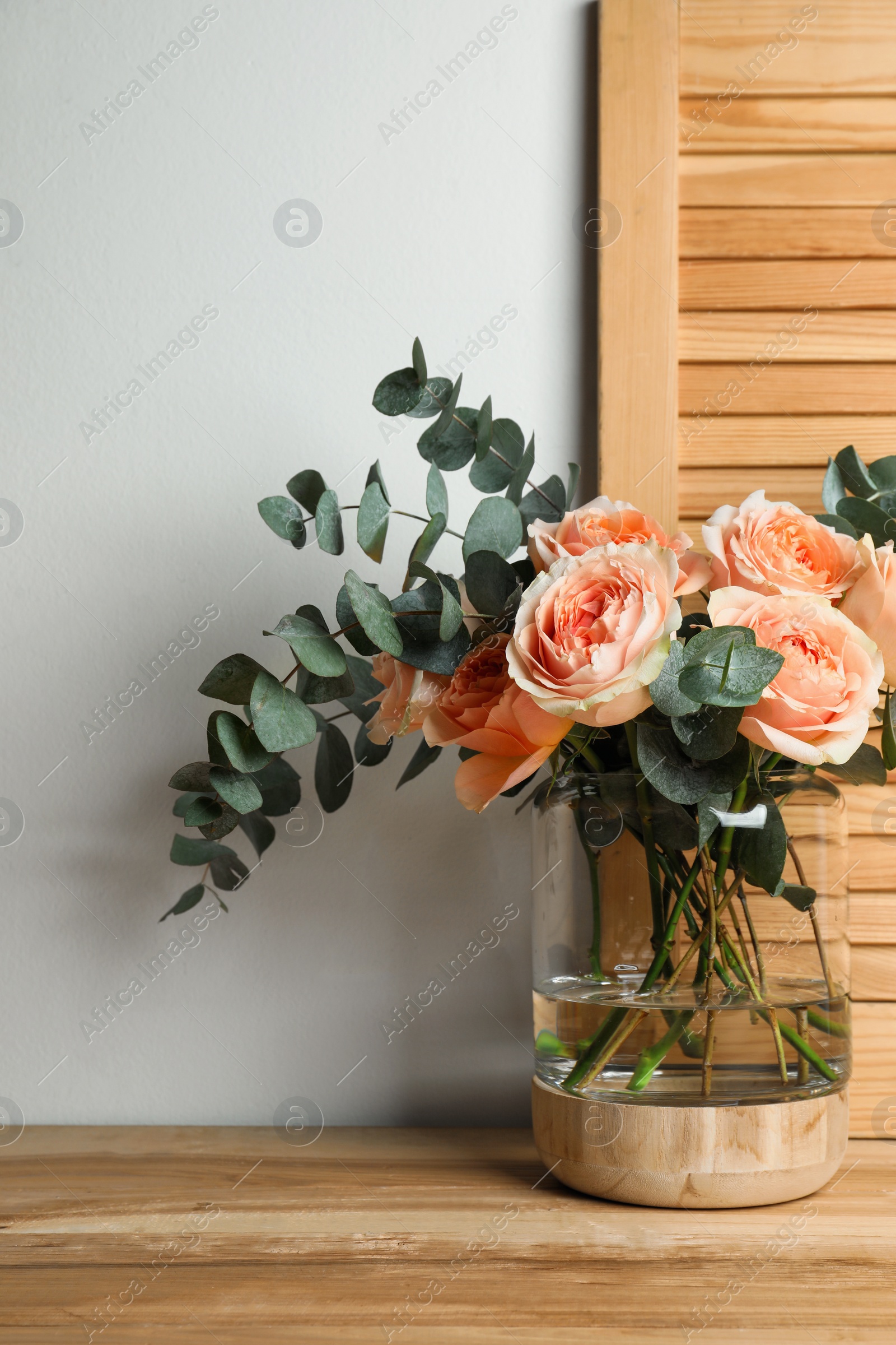 Photo of Bouquet with beautiful flowers in glass vase on wooden table