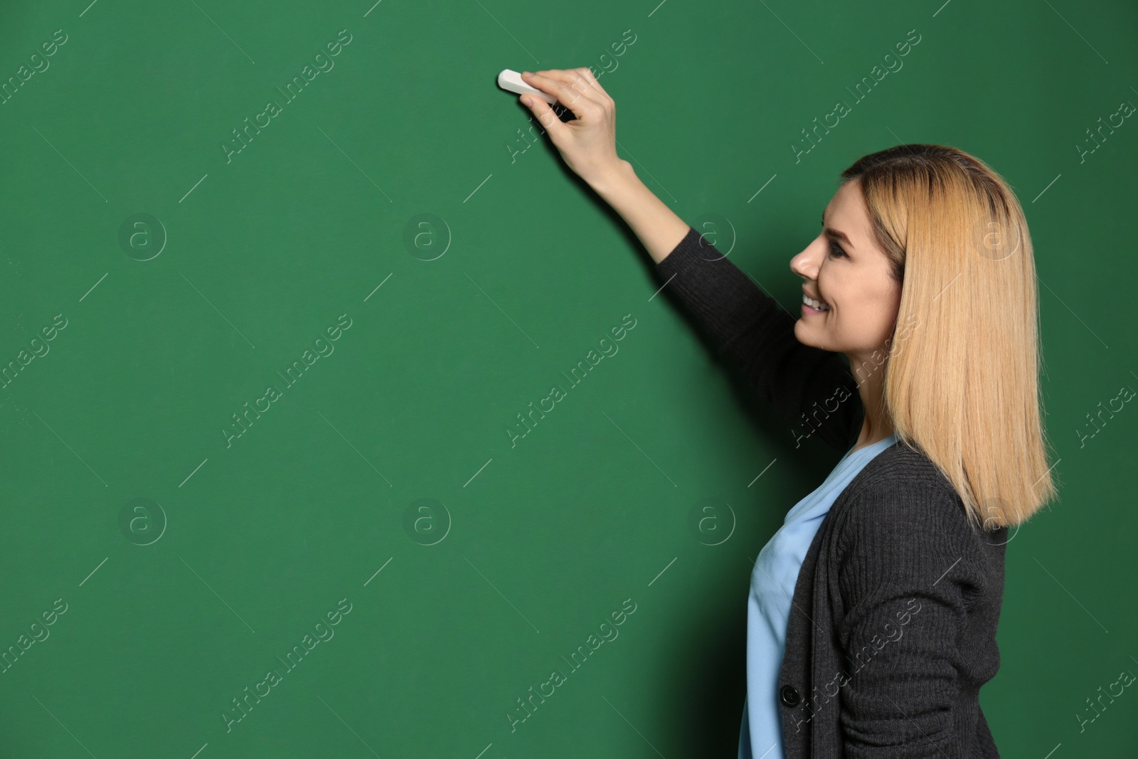 Photo of Beautiful teacher writing on chalkboard, space for text