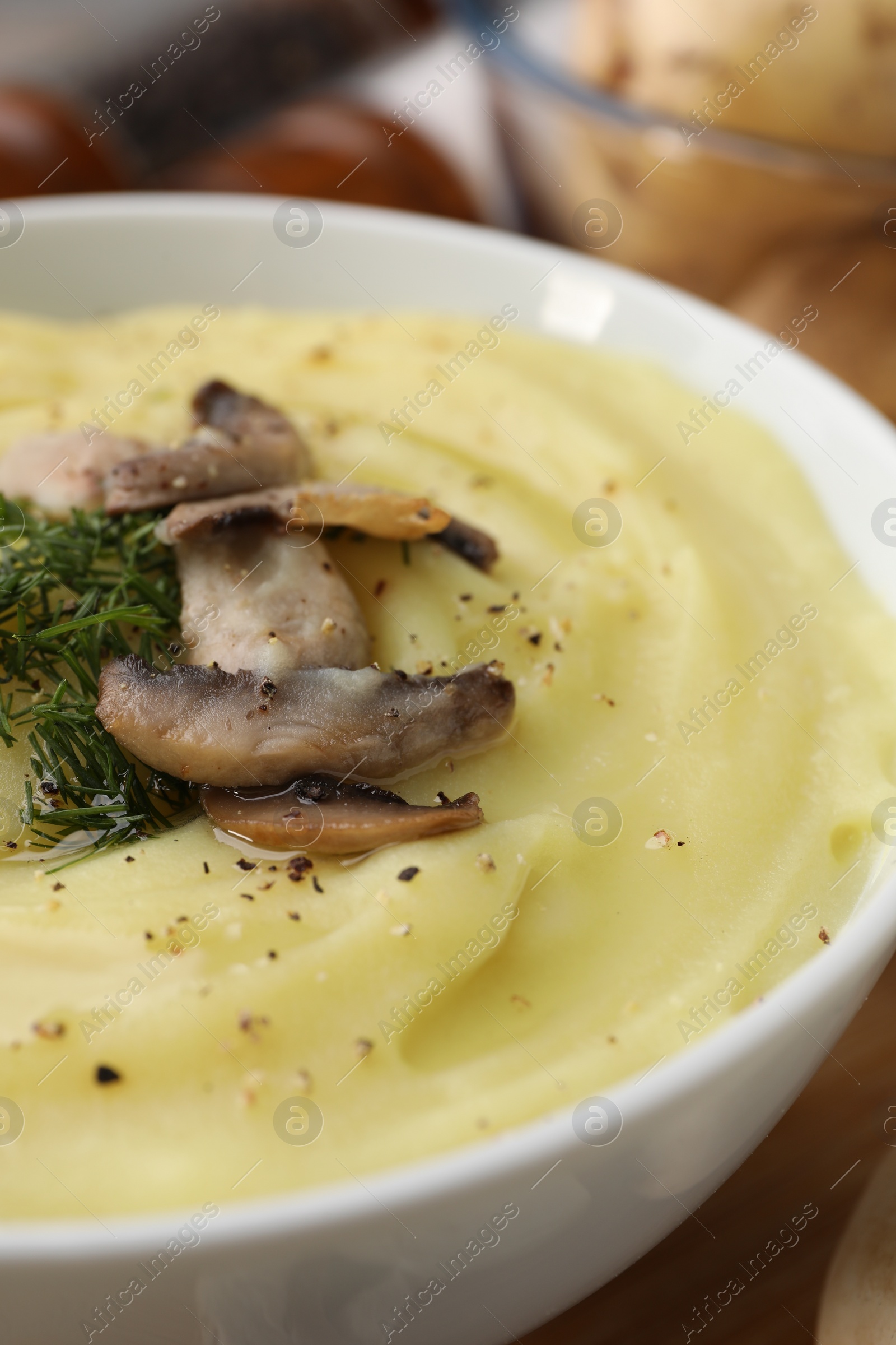 Photo of Bowl of tasty cream soup with mushrooms and dill on table, closeup