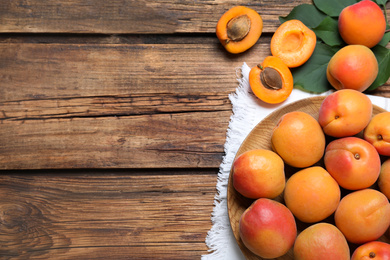 Photo of Delicious fresh ripe apricots on wooden table, flat lay. Space for text