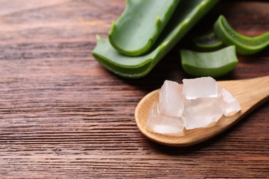 Photo of Aloe vera gel and slices of plant on wooden table, closeup. Space for text