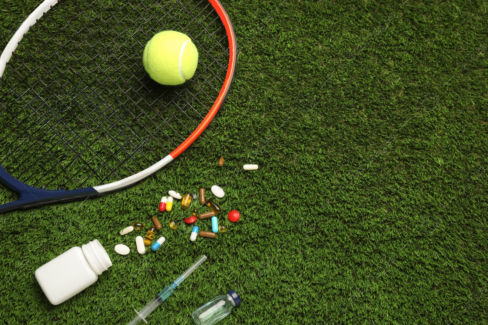 Photo of Tennis racket, ball and drugs on green grass, flat lay with space for text. Doping concept