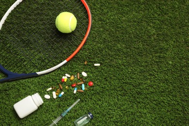 Photo of Tennis racket, ball and drugs on green grass, flat lay with space for text. Doping concept