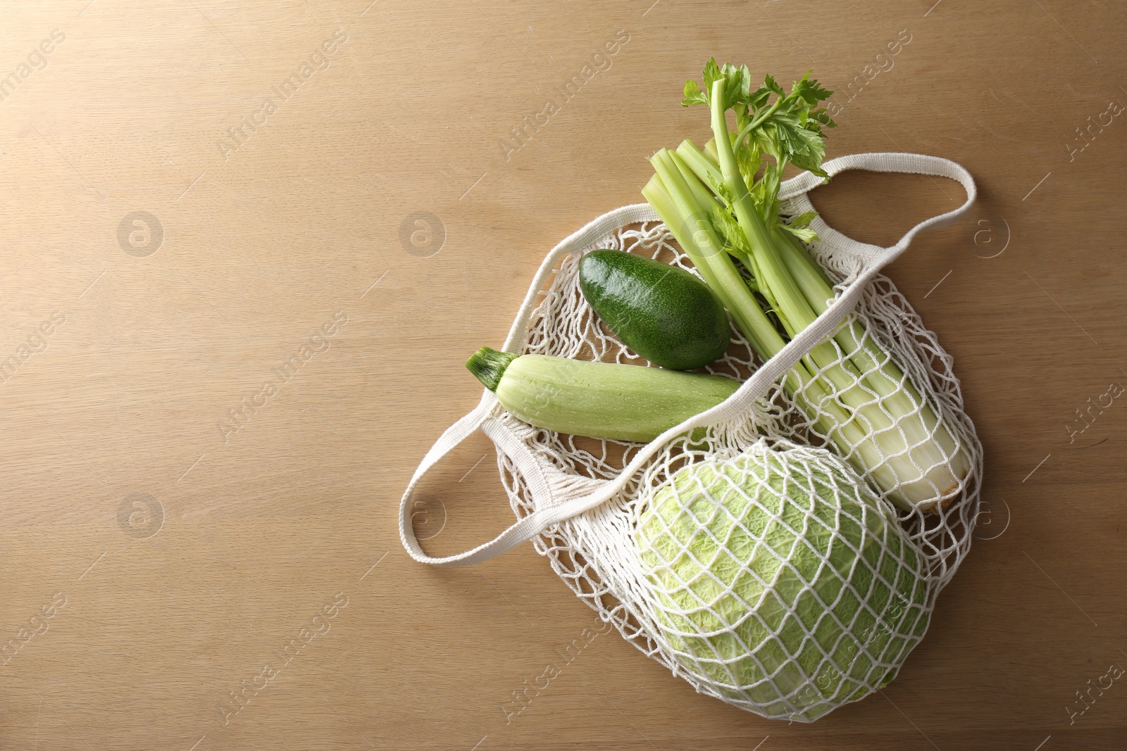 Photo of Different fresh vegetables in eco mesh bag on wooden table, top view