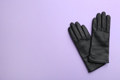 Pair of stylish leather gloves on violet background, flat lay. Space for text