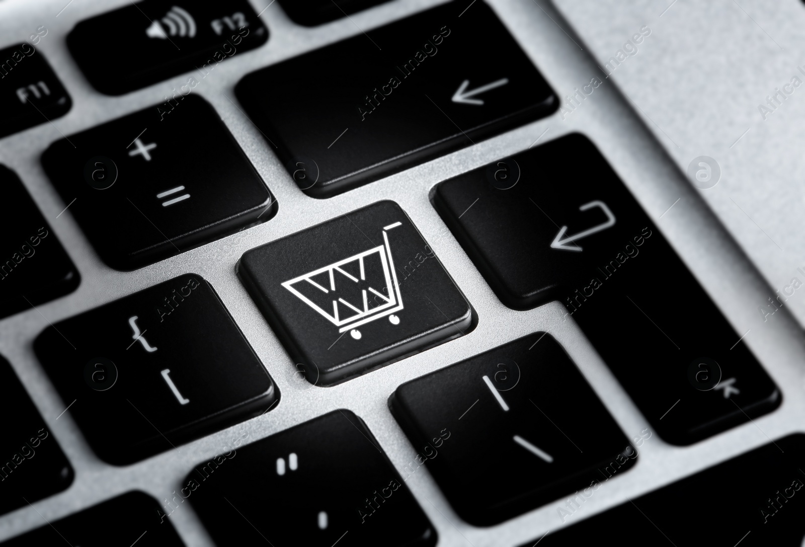 Image of Modern laptop keyboard with cart symbol, closeup view. Internet shopping