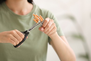 Photo of Stop smoking concept. Woman cutting cigarettes on light background, closeup. Space for text