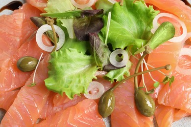 Photo of Delicious salmon carpaccio with capers on plate, top view