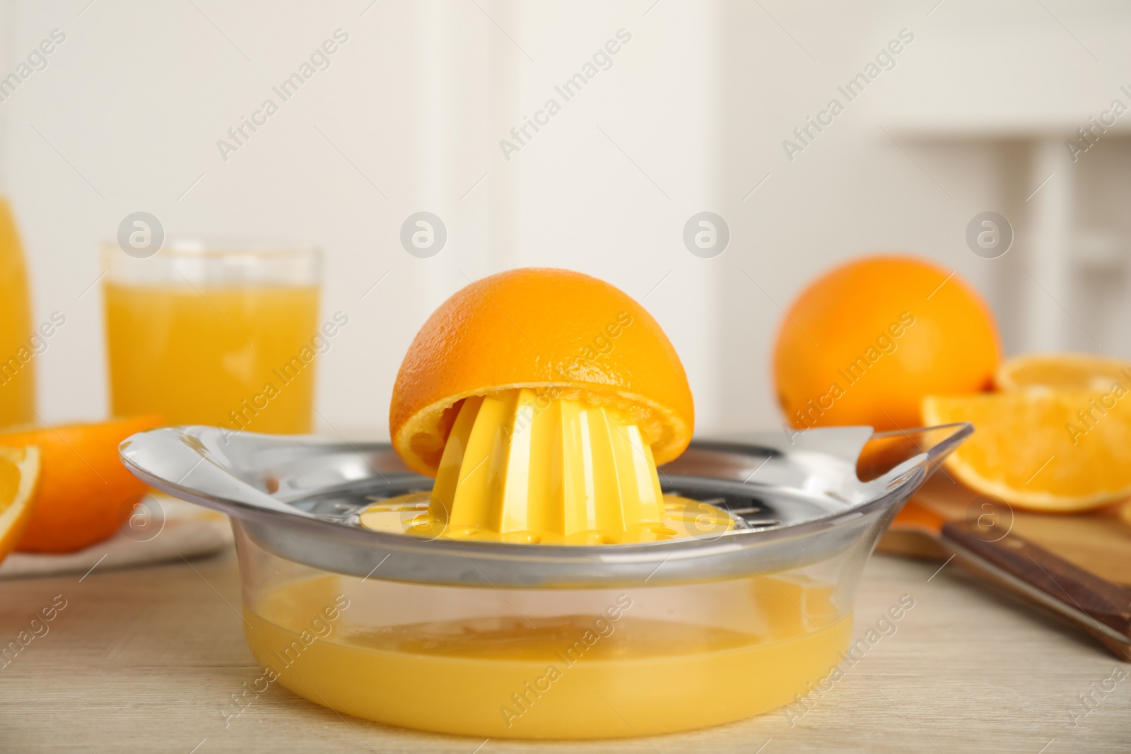 Photo of Cut fresh ripe orange and squeezer on wooden table