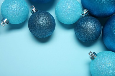 Photo of Christmas balls on light blue background, top view. Space for text