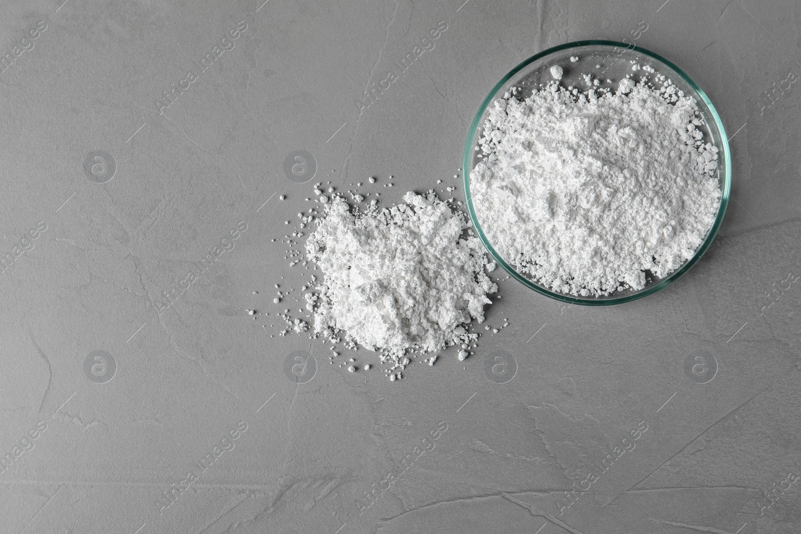 Photo of Petri dish and calcium carbonate powder on grey table, flat lay. Space for text