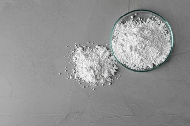 Petri dish and calcium carbonate powder on grey table, flat lay. Space for text