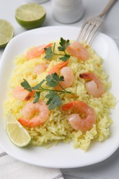 Photo of Delicious risotto with shrimps, lime and parsley on white table, closeup