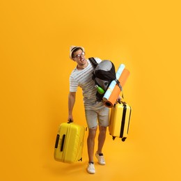 Photo of Male tourist with travel backpack and suitcases on yellow background