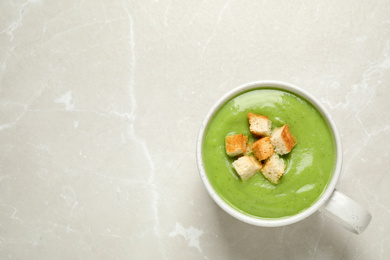 Photo of Tasty homemade zucchini cream soup on light table, top view. Space for text