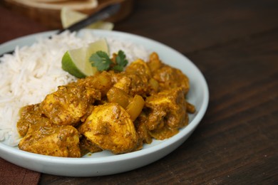 Photo of Delicious chicken curry with rice on wooden table, closeup