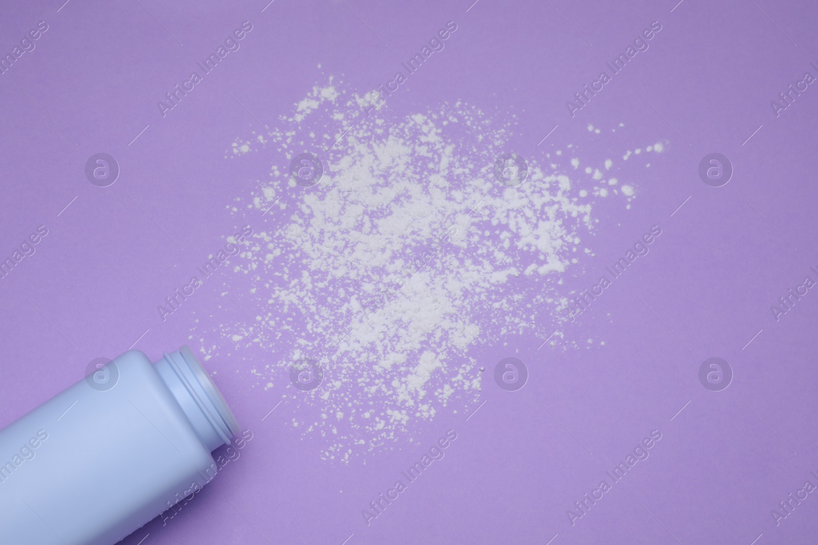 Photo of Bottle and scattered dusting powder on violet background, top view. Baby cosmetic product