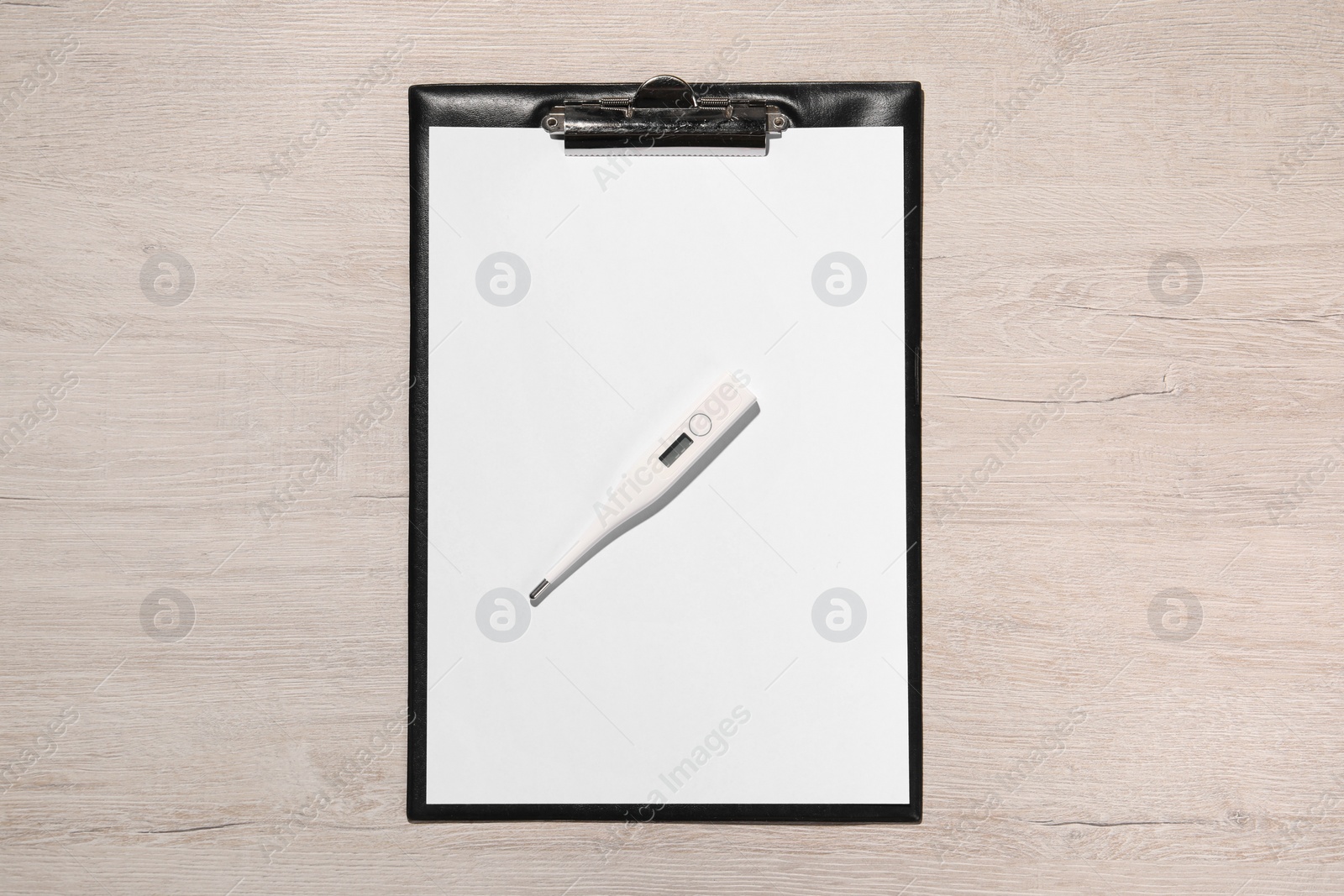 Photo of Clipboard and thermometer on wooden table, top view. Medical treatment