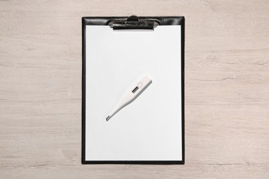 Photo of Clipboard and thermometer on wooden table, top view. Medical treatment