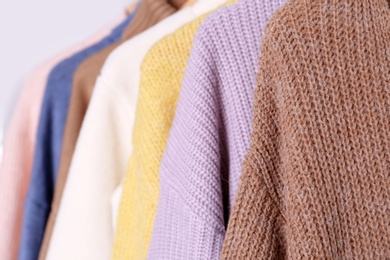 Photo of Warm sweaters hanging on rack, closeup view