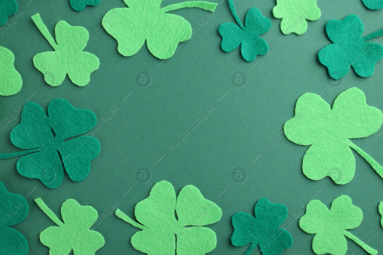 Photo of St. Patrick's day. Frame of decorative clover leaves on green background, flat lay. Space for text