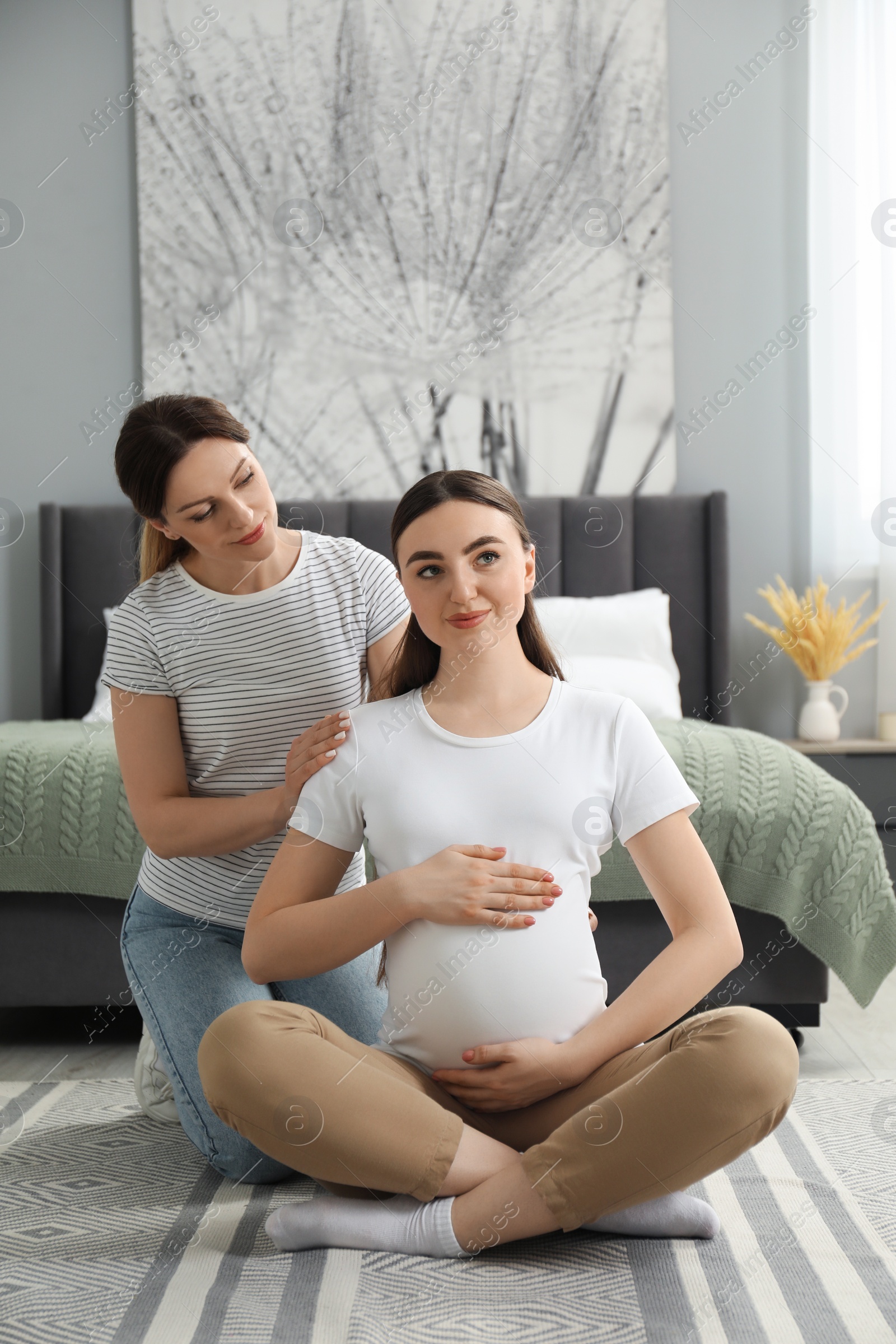 Photo of Doula massaging pregnant woman in bedroom. Preparation for child birth