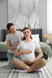 Doula massaging pregnant woman in bedroom. Preparation for child birth