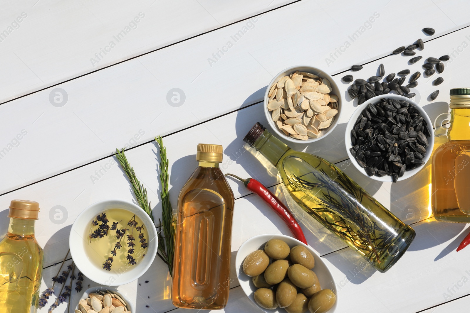 Photo of Different cooking oils and ingredients on white wooden table, flat lay. Space for text