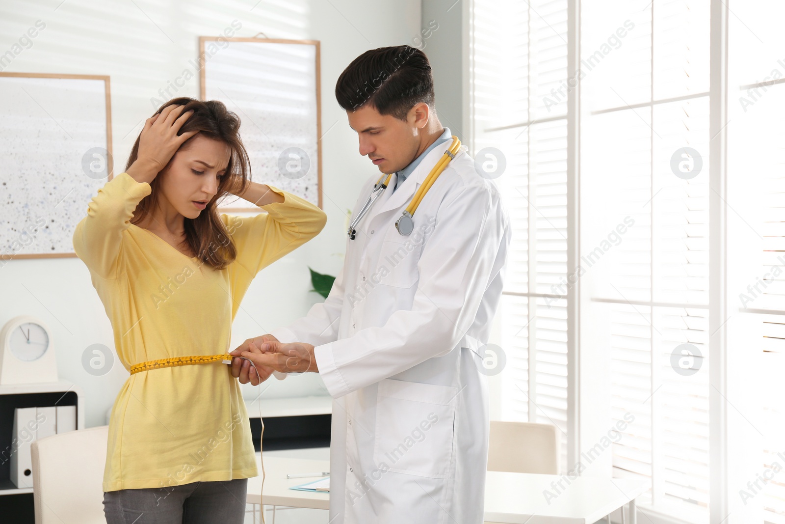 Photo of Nutritionist measuring young patient's waist in clinic