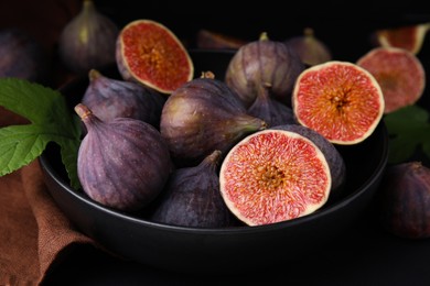 Bowl with fresh ripe purple figs on black table