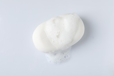 Soap with fluffy foam on white background, top view