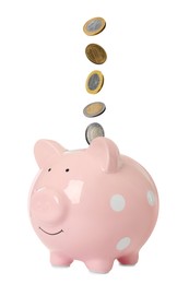 Money falling into pink piggy bank on white background