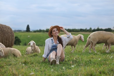 Photo of Smiling woman with sheep on pasture at farm