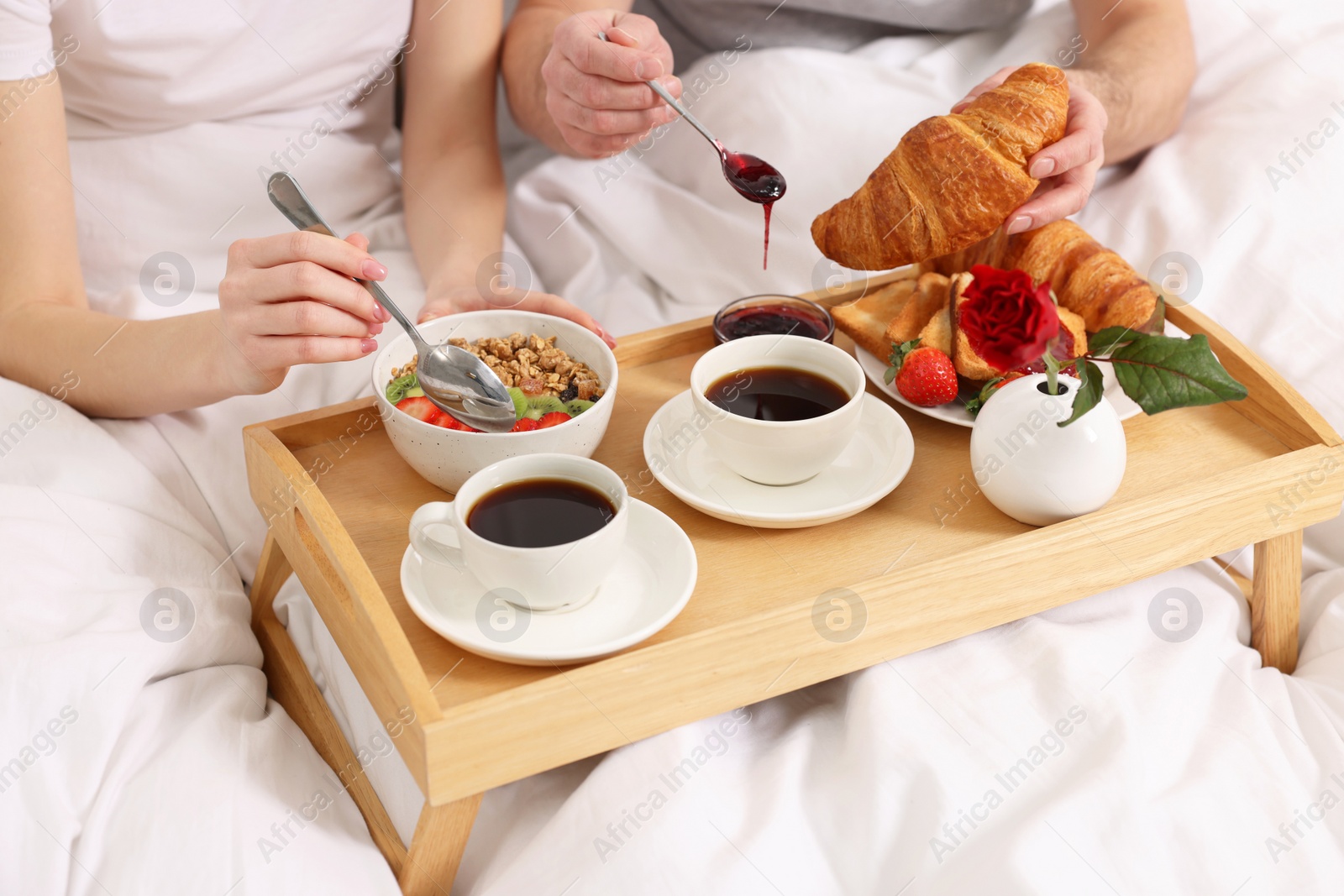 Photo of Couple eating tasty breakfast in bed, closeup
