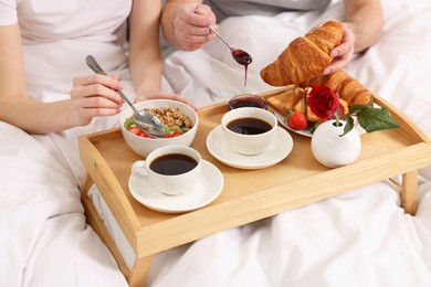 Couple eating tasty breakfast in bed, closeup