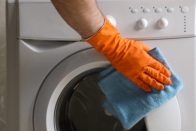 Photo of Man cleaning washing machine with rag, closeup