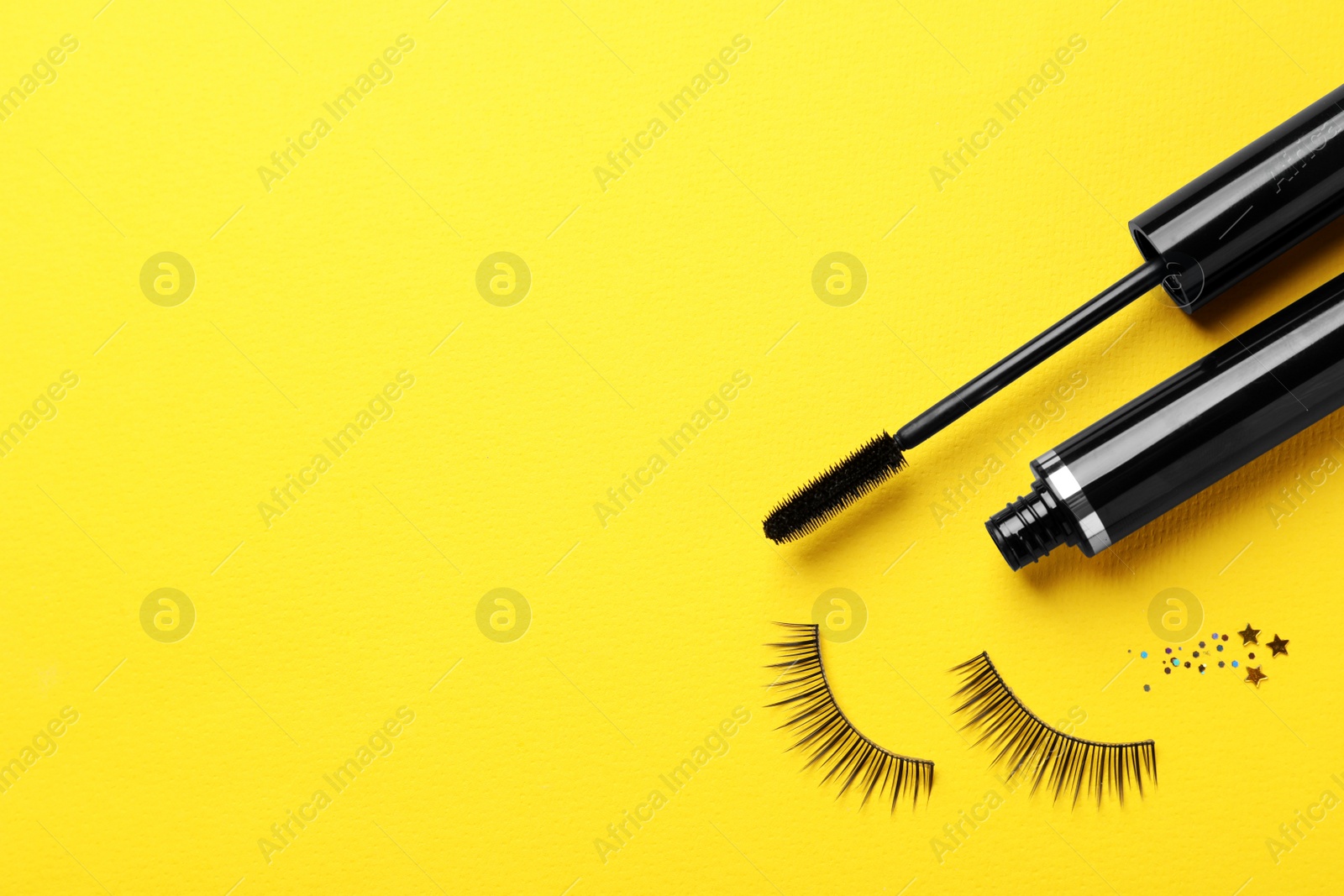 Photo of False eyelashes and mascara on yellow background, flat lay. Space for text