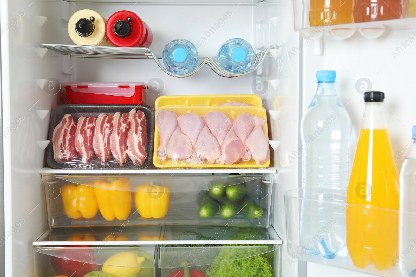 Photo of Open refrigerator with many different products, closeup